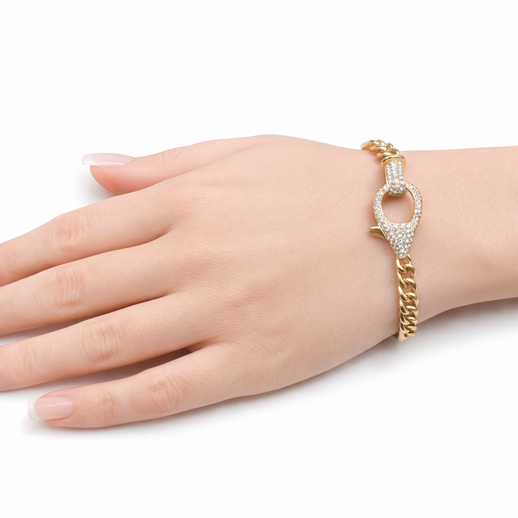 Close up of a 14KT yellow gold Cuban link bracelet with a diamond encrusted lobster clasp worn on hand against a white background showcasing natural diamond detail and polished gold finish