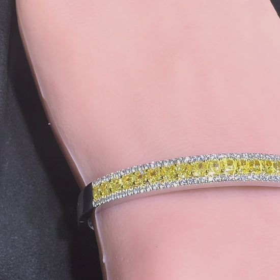 Close up video of 14K white gold bangle bracelet with yellow center diamonds and white diamond halo on wrist Isabella’s Fine Jewelry Huntington Beach Orange County